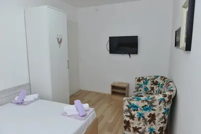 a hotel room with a chair and a tv at Rooms Ela Ela in Prekodolce
