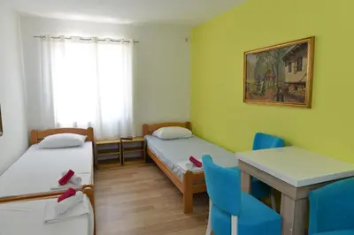 a room with two beds and a table and chairs at Rooms Ela Ela in Prekodolce