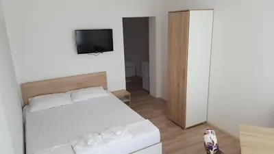 a bedroom with a white bed and a flat screen tv at Rooms Ela Ela in Prekodolce