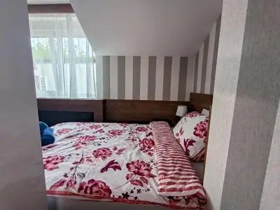 a bedroom with a bed with a red and white comforter at Studio Apartments Maksimović in Niš