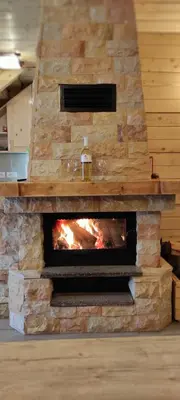 a stone fireplace in a kitchen with a fire place at Vikendica Vila Despotovic in Kopaonik