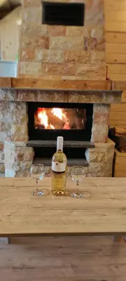 a bottle of whiskey and two glasses on a table with a fireplace at Vikendica Vila Despotovic in Kopaonik