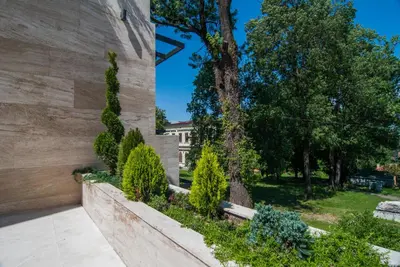 a retaining wall with trees and a building at Vila Opera in Vrnjačka Banja