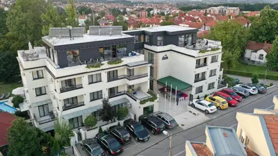 a large white building with cars parked in a parking lot at Vila Opera in Vrnjačka Banja