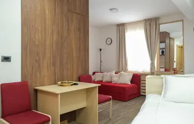 a hotel room with a bed and a red couch at Apartments Pavle in Kopaonik