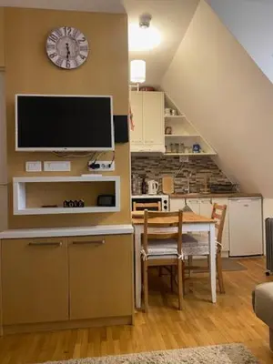 a living room with a table and a clock on the wall at Apartments Pavle in Kopaonik
