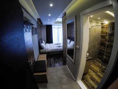 a small room with a bed and a walk in shower at SM Apartments Kopaonik III in Kopaonik