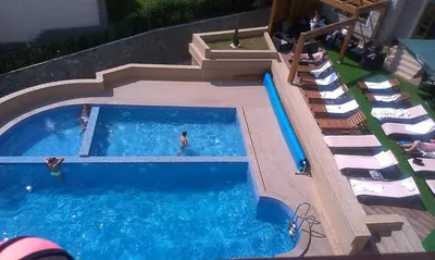 a swimming pool with chairs and a man in the water at Ski & Spa K2 Milmari Resort Lux in Kopaonik