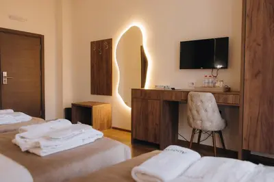 a hotel room with two beds and a desk with a television at Apostolovic Plus in Leskovac