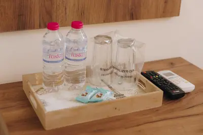 three bottles of water and a remote control on a table at Apostolovic Plus in Leskovac