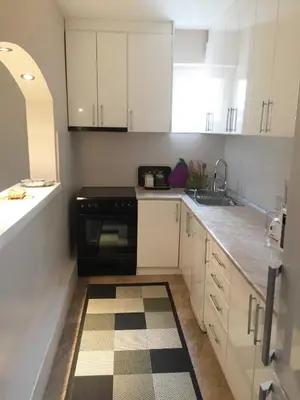 a kitchen with white cabinets and a black stove at Apartment Aloha in Vrnjačka Banja
