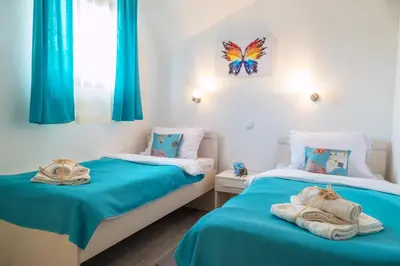 two beds in a room with blue curtains and towels at Apartmani Maja Sokobanja in Soko Banja