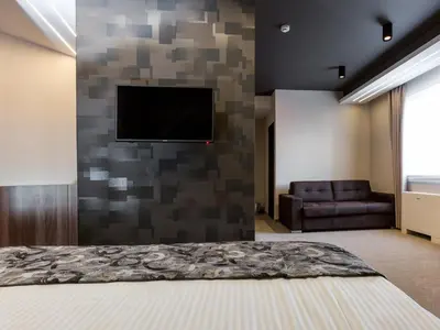 a bedroom with a tv on a stone wall at Hotel Ideo Lux in Niš