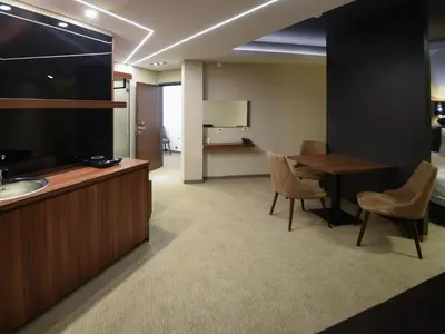 a room with a desk and a table and chairs at Hotel Ideo Lux in Niš