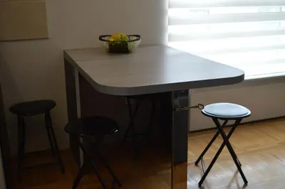 a table with two stools and a bowl of fruit on it at Apartman 33 Kraljevi Čardaci in Kopaonik