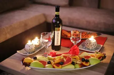 a table with a plate of fruit and a bottle of wine at Astoria Lux - K16 Milmari in Kopaonik