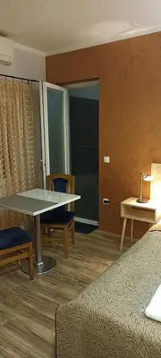 a room with a table and chairs and a bed at Athos Apartments in Niš