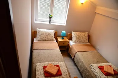 two twin beds in a small room with a window at Athos Apartments in Niš