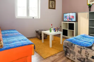 a room with a bed and a table and a tv at Athos Apartments in Niš