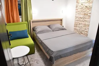 a small bedroom with a bed and a chair at Exclusive Spot FREE parking in Niš
