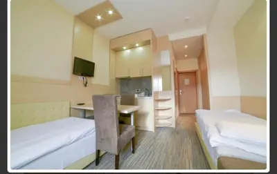 a room with two beds and a desk and a kitchen at Apartments Konaci Centar in Kopaonik