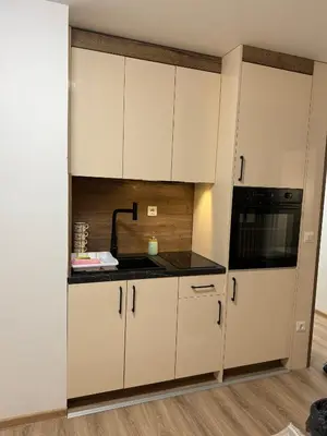a kitchen with white cabinets and a black appliance at Apartments Konaci Centar in Kopaonik