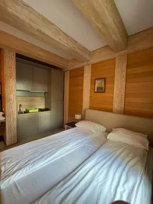 a bedroom with a large white bed with a wooden ceiling at Apartments Konaci Centar in Kopaonik