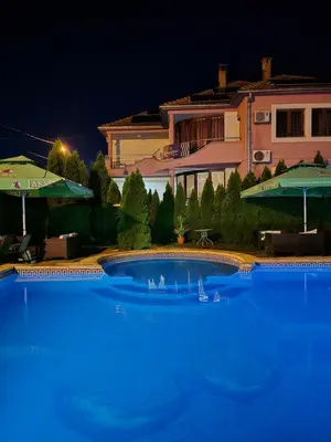 a large blue swimming pool in front of a house at Poseidon Apartment in Niš