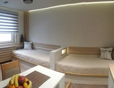 a room with two beds and a table with a bowl of fruit at Apartment Dream Konaci in Kopaonik