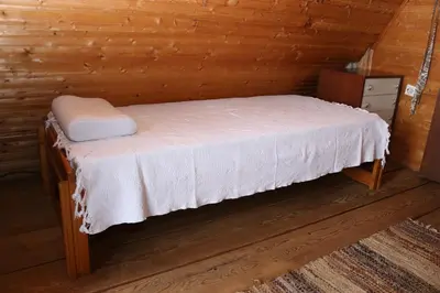 a bed in a wooden cabin with a white mattress at Holiday Home Dana Kopaonik in Kopaonik
