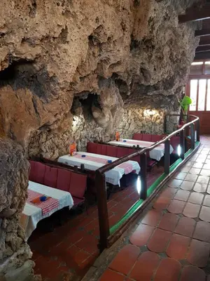 a restaurant in a cave with a stone wall at Guest House Lisinski Raj in Despotovac