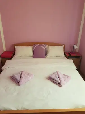 a bed with three purple pillows on it at Guest House Lisinski Raj in Despotovac