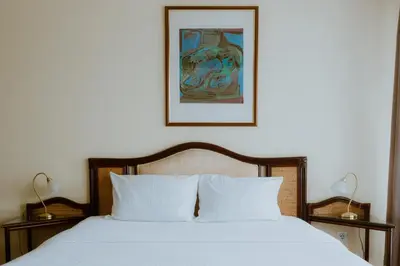 a bed with white sheets and a picture on the wall at Medical and Spa Centre Merkur in Vrnjačka Banja