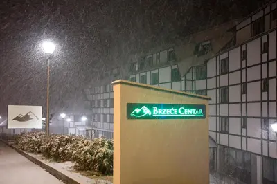 a building with a sign on it in the snow at Brzeće Center Apartments in Kopaonik