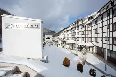 a building with snow on the ground in front of it at Brzeće Center Apartments in Kopaonik