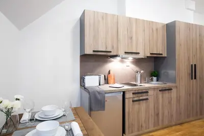 a small kitchen with wooden cabinets and a table at Brzeće Center Apartments in Kopaonik
