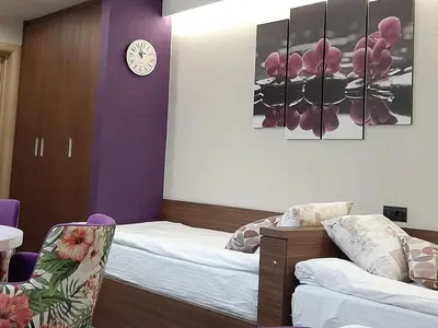 a bedroom with two beds and a clock on the wall at Select Lux Apartments Konaci Kopaonik in Kopaonik