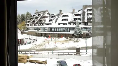 a view of a building in the snow from a window at Select Lux Apartments Konaci Kopaonik in Kopaonik