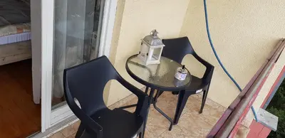 two chairs and a table with a lantern on a porch at Nice apartment in Niš