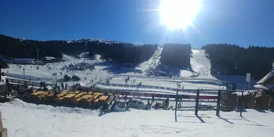 a snow covered ski slope with the sun in the sky at Elite Apartment Konaci in Kopaonik