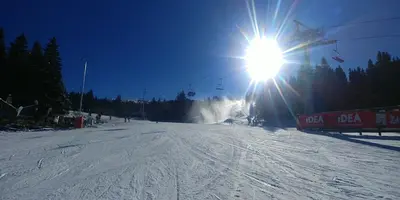 a sun is shining on a snow covered ski slope at Elite Apartment Konaci in Kopaonik