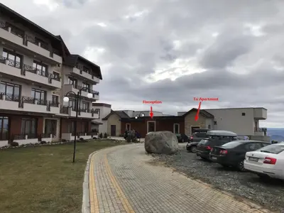 a building with cars parked in a parking lot at Apartment F10 Milmari Resort in Kopaonik