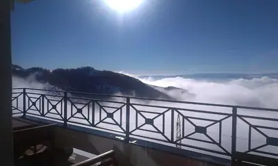 a view of a fog covered mountain with the sun in the sky at Apartment F10 Milmari Resort in Kopaonik