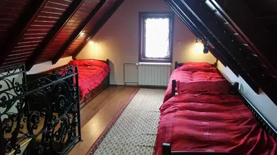 two beds in a small room with red sheets at Planinski Biser in Kopaonik