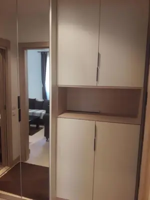a kitchen with white cabinets and a living room at Kamena Kuca Lux Apartment in Kopaonik