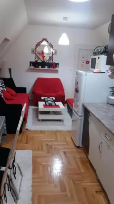 a living room with a red couch and a kitchen at Apartman ČAR 19 in Kopaonik