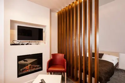 a bedroom with a bed and a fireplace and a red chair at Snow White apartments in Kopaonik