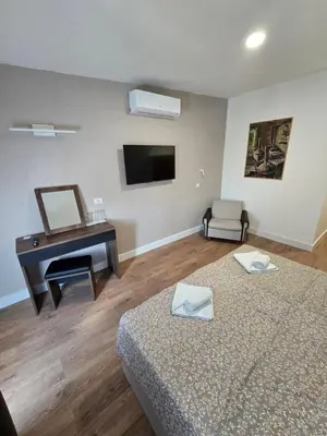 a room with two beds and a desk and a mirror at Hotel Sax Balkan in Dimitrovgrad