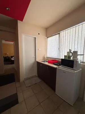 a kitchen with a counter and a refrigerator and a window at Dody Apartmani in Leskovac