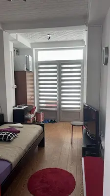 a bedroom with a bed and a window with blinds at Dody Apartmani in Leskovac